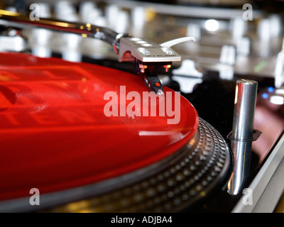 Primo piano di una piattaforma girevole di prelievo ago su un vinile rosso registrazione LP deejay DJ Foto Stock