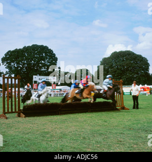 Bambini e pony Shetland avente un grande tempo come essi gara round a uno dei riscaldatori in pony Shetland Grand National Foto Stock