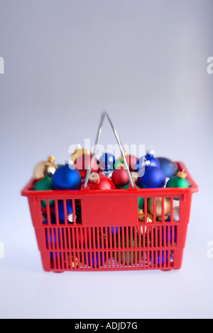 Sfocato colorato albero di Natale ornamenti della lampadina ammassati in rosso carrello con candy canes su sfondo bianco ritratto in studio Foto Stock