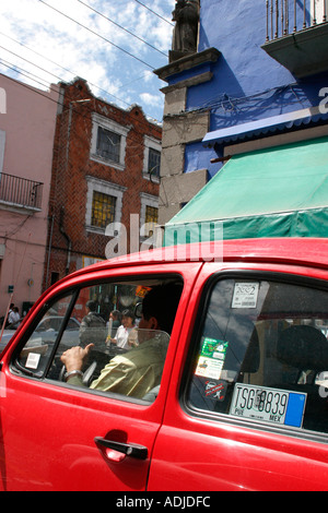 Red Volkswagen maggiolino taxi di fronte color pastello edifici coloniali in una strada in Cholula Messico Foto Stock