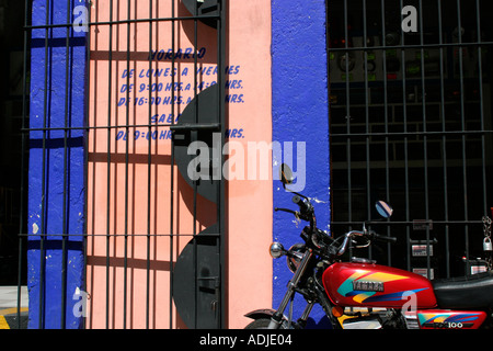 Vivacemente colorato yamaha moto al di fuori di un rosa salmone e blu luminoso negozio su un messicano di angolo di strada. Foto Stock