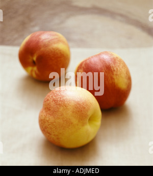 Tre le nettarine su lino e ardesia naturale sullo sfondo Foto Stock