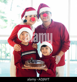 Una famiglia coreana è messa su un Babbo Natale del cappello e tenendo una torta Foto Stock