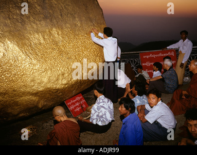 Myanmar Kyaik Hti Yo Golden Rock Pagoda dedica pregando e applicare la foglia di oro Foto Stock