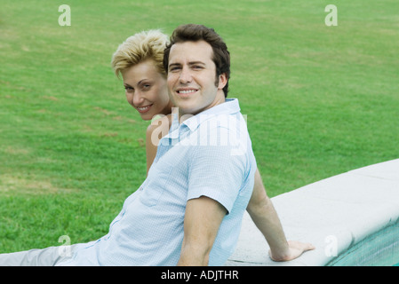 Giovane seduti in piscina insieme sorridente in telecamera Foto Stock