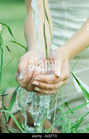 Donna mani a tazza sotto acqua corrente Foto Stock