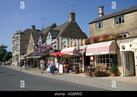 I turisti in visita nei piccoli negozi di Main Street Bourton sull'acqua Costwolds REGNO UNITO Foto Stock