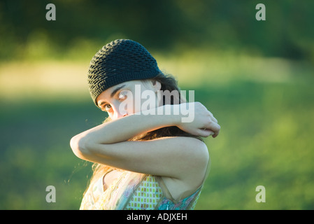 Giovane donna tenendo premuto fino a gomito, guardando oltre il braccio alla fotocamera Foto Stock