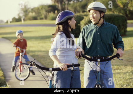 I genitori su biciclette con il loro figlio in piedi dietro di loro Foto Stock