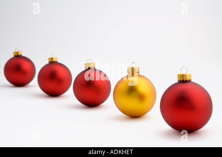 Guardando verso il basso su una d'oro albero di Natale ornamento della lampadina in linea con quattro lampadine rosso su sfondo bianco ritratto in studio Foto Stock