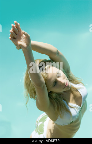 Giovane donna in piedi in bikini con le mani sopra la testa Foto Stock
