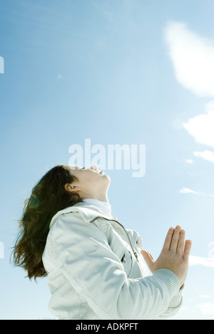 Teen ragazza con le mani incrociate a occhi chiusi e la testa indietro e a basso angolo di visione Foto Stock