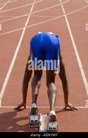 Runner maschio Accovacciata sui blocchi di partenza Foto Stock