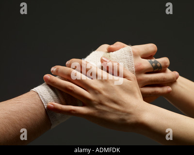 Coppia di mani tenendo un altro mano bendato close up Foto Stock