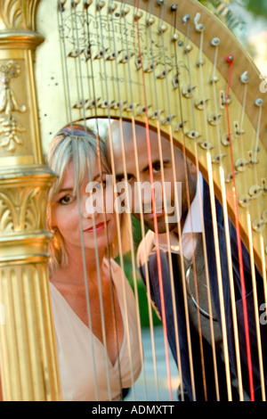 Uomo nero e una donna bianca con arpa in primo piano Foto Stock