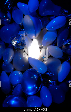 Singola candela opale lampadina luce brilla su uno sfondo di utilizzate lampadine elettriche/lampade con sfondo blu. Foto Stock