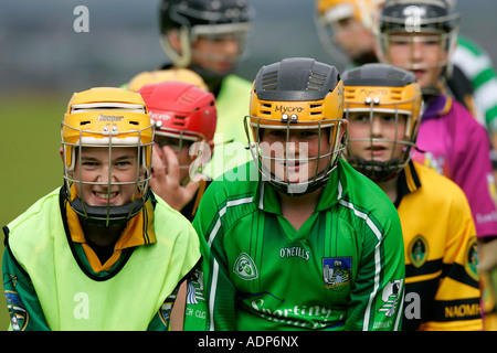 Ragazzi adolescenti che indossa caschi protettivi line up per buttare in prima una pratica hockey irlandese match indossando gaa camicie Foto Stock