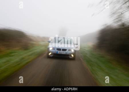 La BMW serie 5 unità auto lungo vuoto country road in avverse condizioni meteo foggy Oxfordshire England Regno Unito Foto Stock