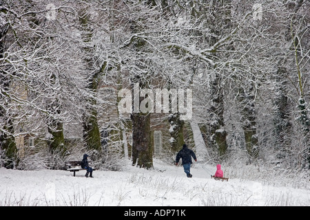 Uomo tira bambino su una pista da slittino in inverno s giornata sulla neve coperto Hampstead Heath London Regno Unito Foto Stock