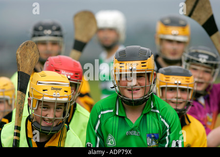 Ragazzi adolescenti che indossa caschi protettivi line up per buttare in prima una pratica hockey irlandese corrispondono holding camans bastoni Foto Stock