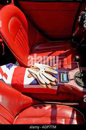 Interni in pelle rossa Austin Healey Sports Car degli anni Sessanta con guanti da guida Stringback e bandiera britannica Foto Stock