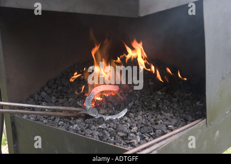 Ferro di cavallo su fornace all'aperto tenuto dal fabbro per aver girato cavallo su Portable Forge in Scozia, Regno Unito Foto Stock