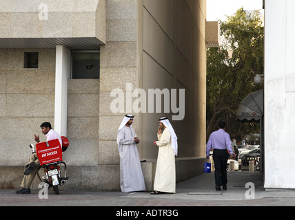 Due uomini arabi in costume tradizionale a conversare in street, Dubai Foto Stock