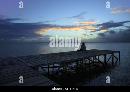 Giovane su un molo al tramonto Foto Stock