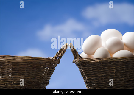 Una cesta vuota e un cesto pieno di uova in esterni con cielo blu Foto Stock