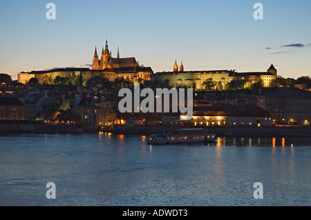Repubblica Ceca Praga vista sul fiume Moldava verso il castello e la Cattedrale di San Vito al tramonto ed una crociera sul fiume in barca per visite guidate Foto Stock