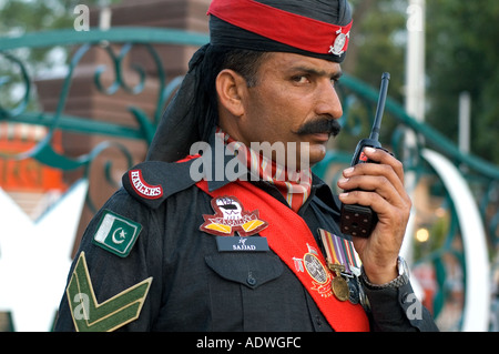 Soldato pakistano a bandiera cerimonia di abbassamento sull'India Pakistan border parlando su un walkie-talkie Foto Stock