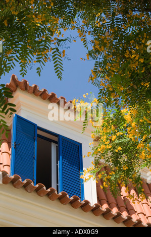 Blu finestra ritagliata nel tetto di una casa con giallo a fiore di Acacia o eventualmente Robinia pseudoacacia tree al di fuori, Lisbona, Portogallo Foto Stock