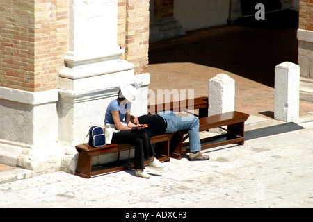 Paio di turisti in appoggio su una panchina in piazza dell'importante Basilica di Loreto nelle Marche Italia Foto Stock