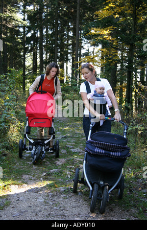 Due donne a piedi con bambino trasporto attraverso la foresta Foto Stock