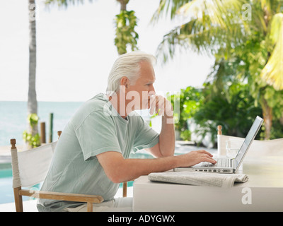 Uomo con notebook al tavolo esterno, vista laterale Foto Stock