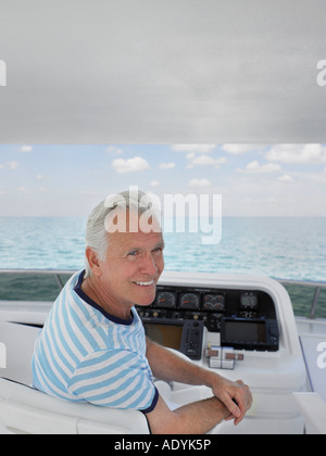 Uomo di mezza età seduto al timone della barca, sorridente Foto Stock