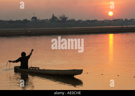 Pescatore in barca al tramonto sul fiume Mekong Foto Stock