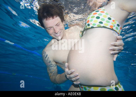 Incinta giovane nuoto nella piscina terapia di coppia Foto Stock