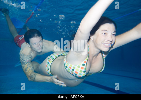 Incinta giovane nuoto nella piscina terapia di coppia Foto Stock