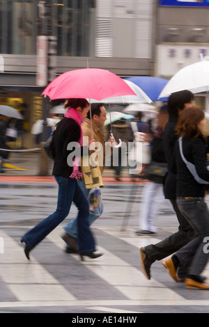 Asia Giappone Honshu Tokyo Shibuya pedoni che attraversano un incrocio occupato con ombrelloni in un giorno di pioggia Foto Stock