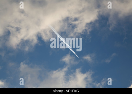 Velivolo che lascia una pista di vapore in cielo blu con spia nuvole bianche Foto Stock