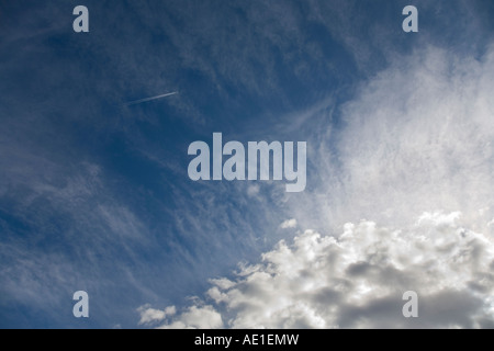 Velivolo che lascia una pista di vapore in cielo blu con spia nuvole bianche Foto Stock