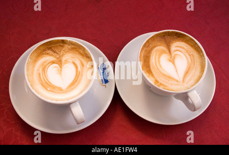 Due bianchi tazze da caffè a forma di cuore in schiuma su rosso tovaglia Roma Italia Foto Stock