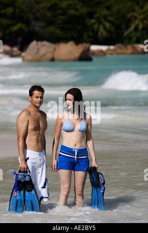 Coppia giovane wading in le onde che si infrangono sulla spiaggia di Anse Lazio Praslin Seychelles Foto Stock