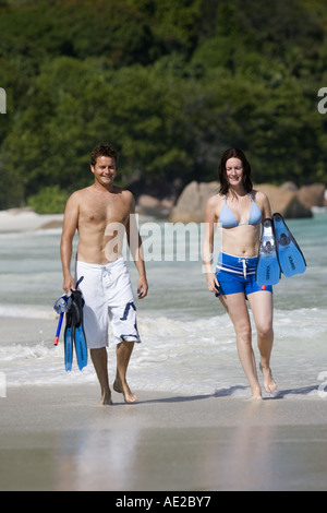 Coppia giovane wading in le onde che si infrangono sulla spiaggia di Anse Lazio Praslin Seychelles Foto Stock