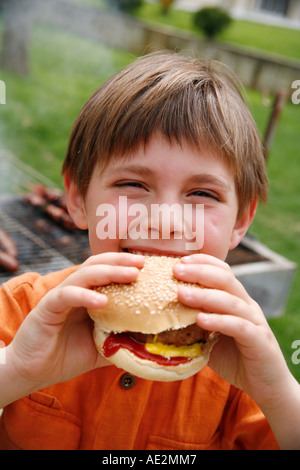 Little Boy mangiare un hamburger Foto Stock