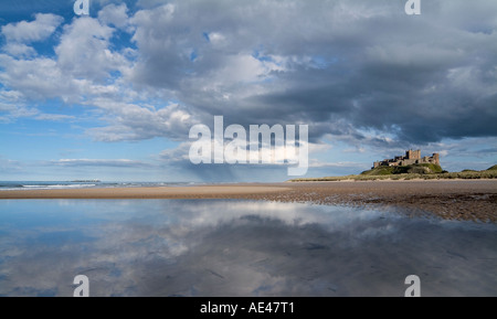 Riflessi del cielo e il castello di Bamburgh sulla spiaggia Bamburgh, Northumberland, Regno Unito Foto Stock