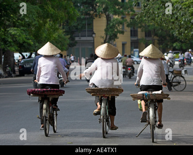 Tre donne in cappelli conici su biciclette Hanoi Vietnam Foto Stock