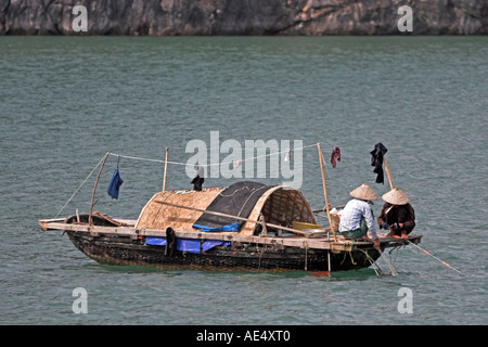 I pescatori in cappelli conici partecipare alle reti di piccole dimensioni in tessuto tradizionale barca da pesca di Halong Bay Vietnam Foto Stock