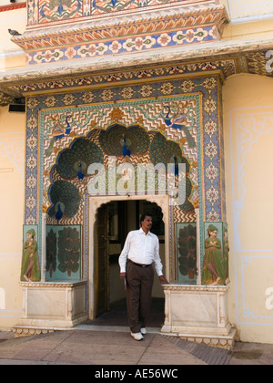 La città di Jaipur Palace - porta circondato da elaborare verniciato design Pavone uomo asiatico a piedi fuori dalla porta al cortile Foto Stock